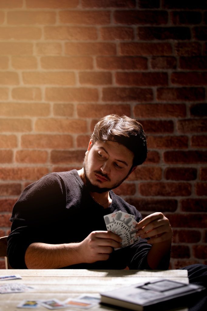 Man gambling with playing cards, symbolizing addiction and its impact on mental health.